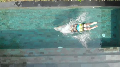 A man in beach clothes jumps into the private pool. Slow motion. Stock Footage 103963773