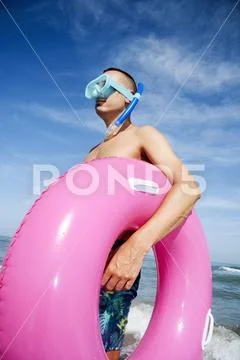 Man on the beach with diving mask and swim ring Stock Photos