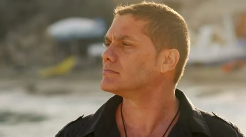 A man at the beach during magic hour turns and looks into camera Stock Footage 33847795