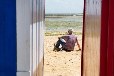 Man on the beach in front of beach huts Stock Photos