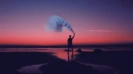 Man On Beach Holding Smoke Canister At Sunset Cinemagraph Stock Footage