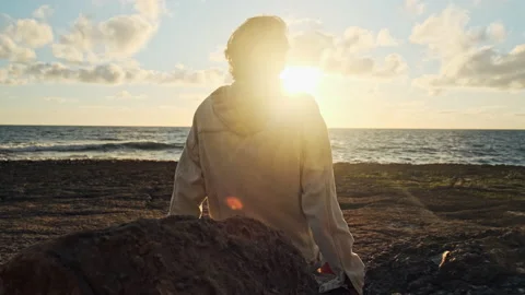 Man on a beach is looking distance during beautiful summer sunset. Video stock 198685347