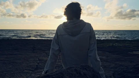 Man on a beach is looking distance during beautiful summer sunset. Stock Footage 304101163