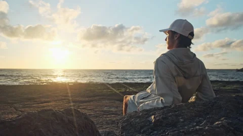 Man on a beach is looking distance during beautiful summer sunset. Stock Footage 306636172