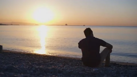 Man at beach looking at sunset view, relaxing in nature Stock Footage 133260909