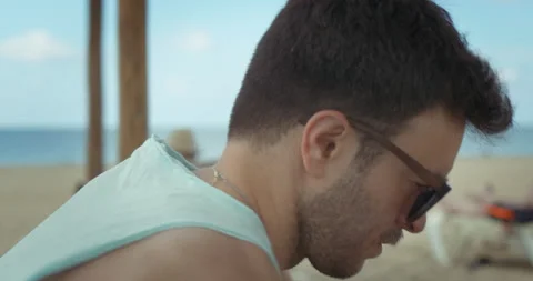 Man on the beach looks at the stuff he brought with him Stock Footage 205022721