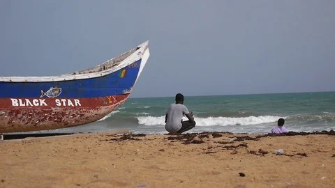 Man on the beach next to black star pirogue Stock Footage 81219206