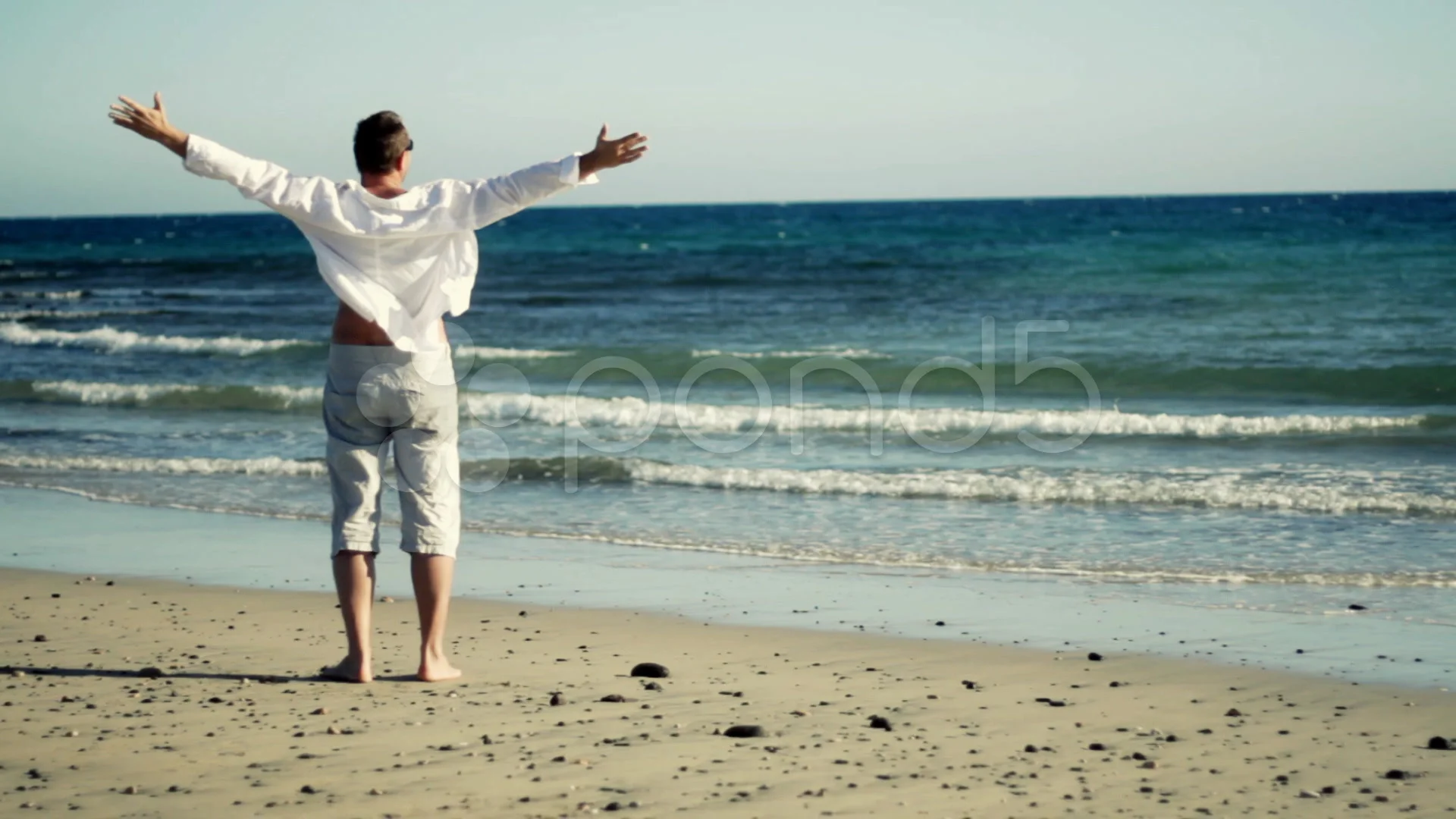 Man at the beach raising hands to the sky freedom concept