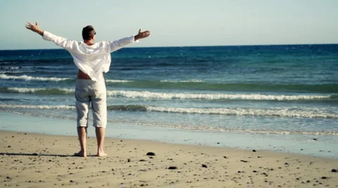 Man at the beach raising hands to the sky, freedom concept  Stock Footage 1081304