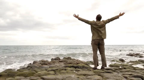 Man at the beach rising hands to the sky Stock Footage 1055666