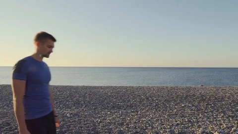 A man on the beach sets up a smart watch before training. A male runner looks at Stockbeeldmateriaal 118228488