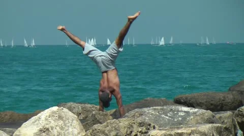 Man on the beach stand on his hands Stock Footage 22146790