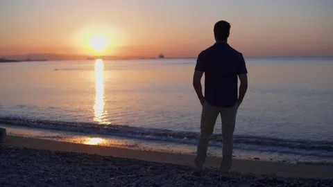 Man on beach vacation relaxing looking at sea sunrise view Stock Footage 133259897