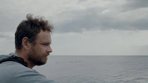 A man with a beard against the background of the sea, taking a photo Stock Footage 115480510