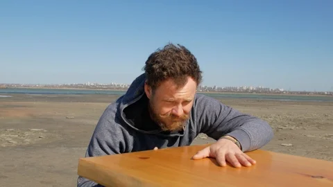 Man with a beard against a blue sky touches the surface of the table Stock Footage 104898415
