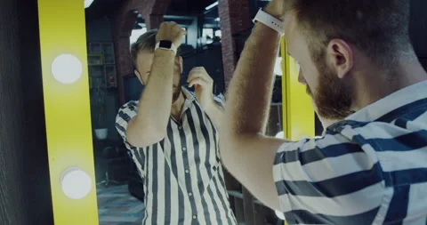 Man with a beard and arranges his hair in a large mirror lit with light bulbs. Stock Footage 139756997