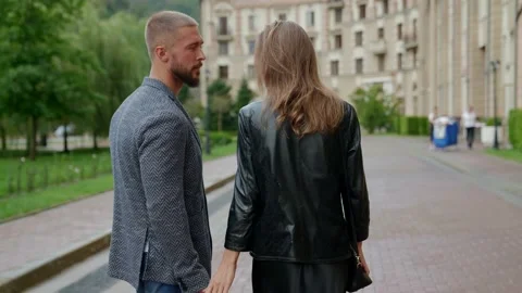 A man with a beard and a blonde in a black jacket walk along the path between Stock Footage 170285506