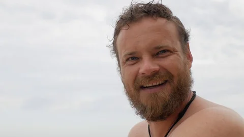 Man with a beard and blue eyes after swimming in the sea emotionally talks Stock Footage 108113016