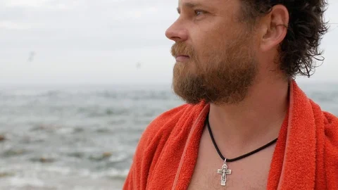 Man with a beard and a cross on his chest against the background of the sea Stock Footage 108112938