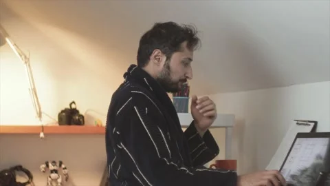 A man with a beard and a dressing gown works at a laptop against the background Stock Footage 150563668