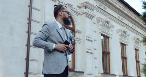 A man with a beard and glasses arranges his jacket on the street of a city! Stock-Footage 139966012