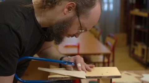 Man with beard and in glasses cuts outdated jetliner model Stock Footage 127112812