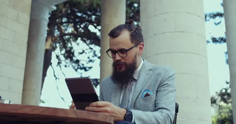 A man with a beard and glasses, dressed for business, uses a tablet Video stock 138858875