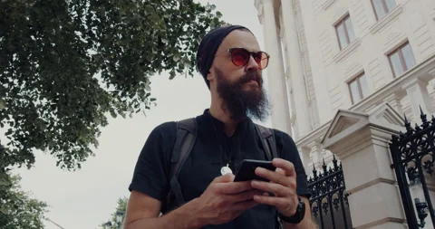 A man with a beard and glasses, walks with the phone in his hand Stock Footage 138813635