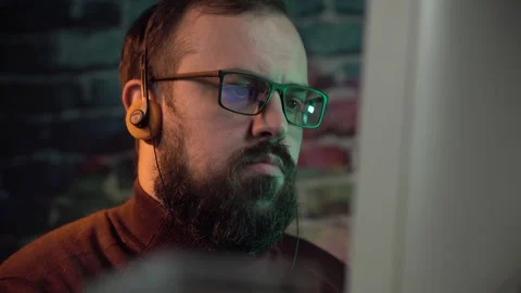 Man With Beard and Glasses Working on Desktop Computer While Listening Audio Stock Footage 306057946