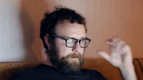 A man with a beard and glasses works at the computer at home. The concept of Stock Footage 119974832