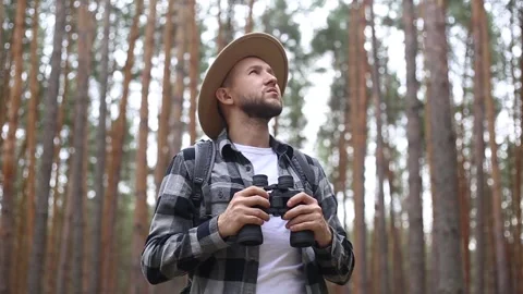 Man with a beard and a hat with binoculars walking in the woods. Stock Footage 149959087