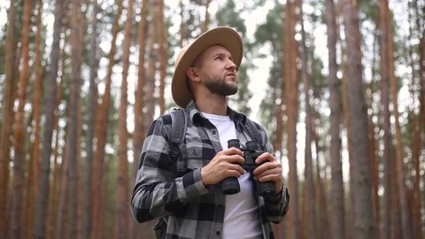 Man with a beard and a hat with binoculars walking in the woods. Stock Footage 149959088