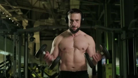 A man with a beard and headphones does a bicep exercise. Healthy lifestyle Video stock 234326756