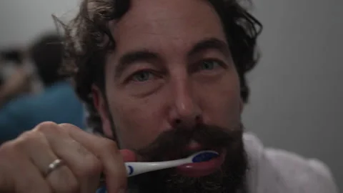 Man with a beard and mustache brushing his teeth in the bathroom Stock Footage 336624745