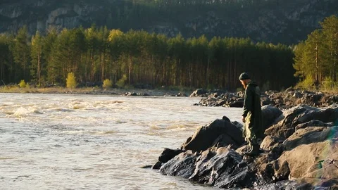 Man with a beard and mustache is drawing water from a river with a bucket Stock Footage 111499834