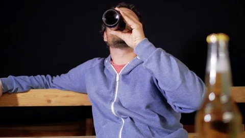 A man with a beard and mustache is drinking dark beer from a bottle Stock Footage 105840574