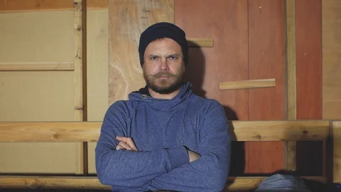 A man with a beard and mustache in a knitted hat crossed his arms and frowned Stock Footage 102941893