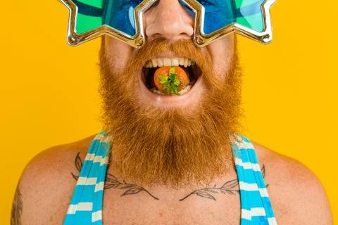 Man with beard and sunglasses eats a strawberry Stock Photos