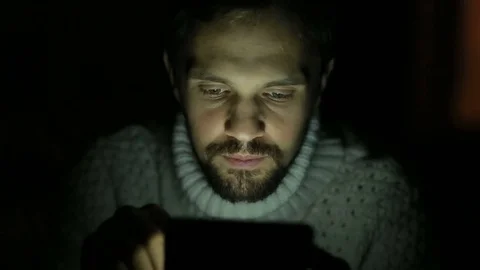 Man with a beard and a sweater with a tablet in the dark Stock Footage 70711515