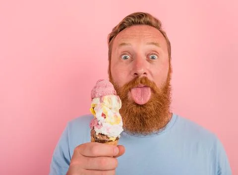 Man with beard and tattoos eats a big icecream Foto stock