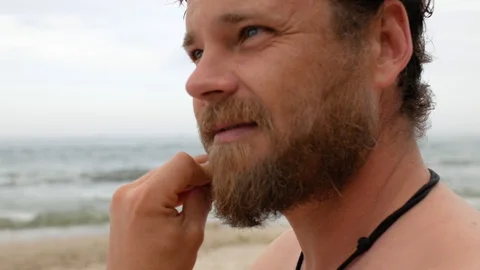 Man with a beard on the background of the sea is combing his beard with a comb Stock Footage 108113086