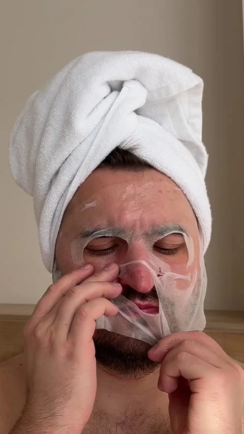Man with beard, bare shoulders, towel on head is trying to put on and tears mask Stock Footage 304361571