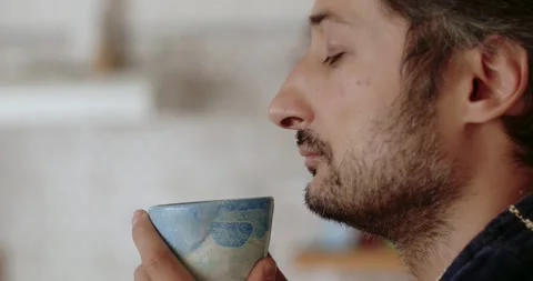 A man with a beard in a bathrobe drinks coffee on the background of the kitchen Stock-Footage 259167831