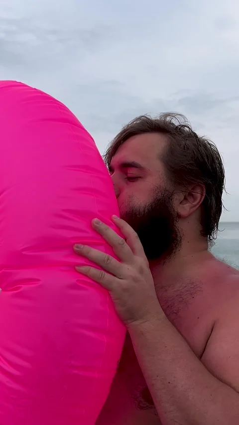 Man with beard, big belly inflates pink magenta inflatable ring for swimming Stock Footage 329666760