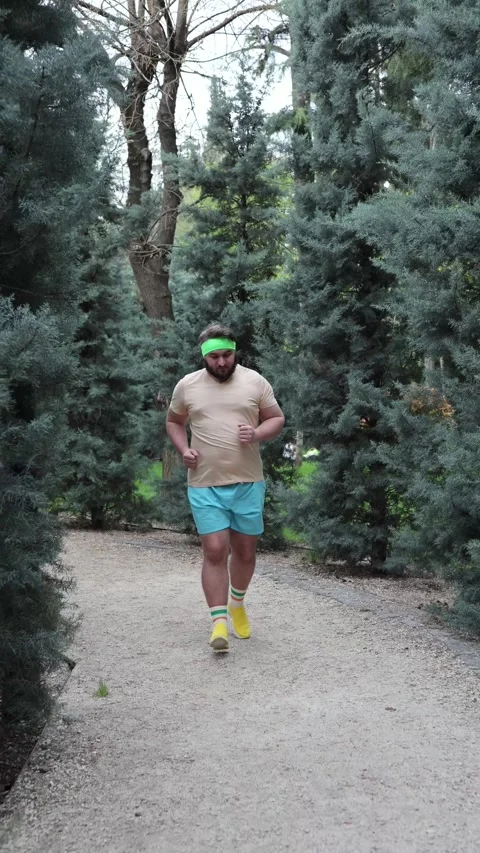 Man with beard, big belly runs along path in city park Stock Footage 306988659