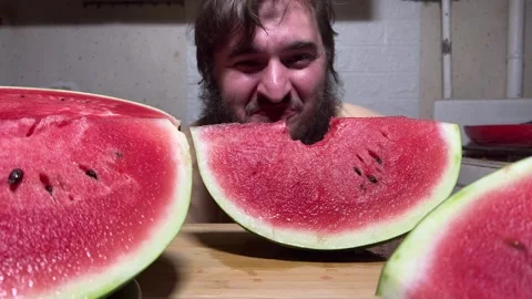 Man with beard bites slice of fresh juicy red raw sweet watermelon Stock Footage 283855394