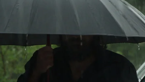 A man with a beard, brutal stands under an umbrella in heavy rain Stock Footage 109563296