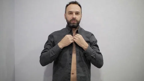 Man with a beard is buttoning his shirt Stock Footage 98808575