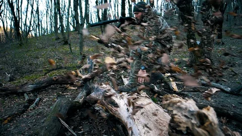 Man with a beard in camouflage with a weapon survives in the autumn forest Stock Footage 128122071