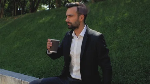 Man with a beard in a classic suit drinks coffee from a disposable cup. 4k Stock Footage 113903814